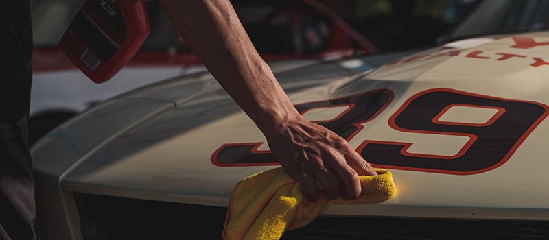 man wiping a racecar with a microfiber cloth